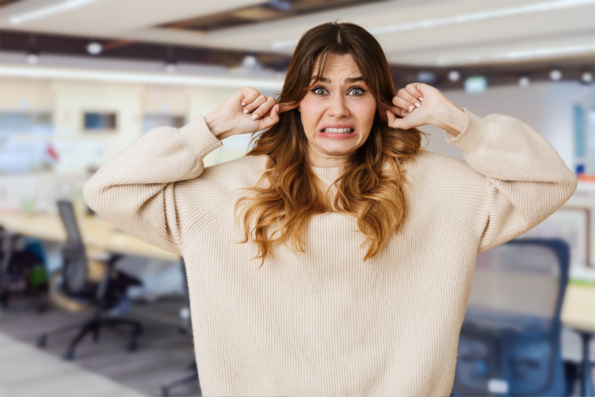 Girl covering her ears with her fingers, eyes shut, overwhelmed by loud noise, illustrating ADHD hypersensitivity.